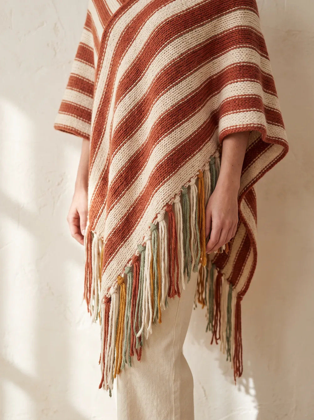 Poncho na drutach w pasy terakoty i kremu z frędzlami